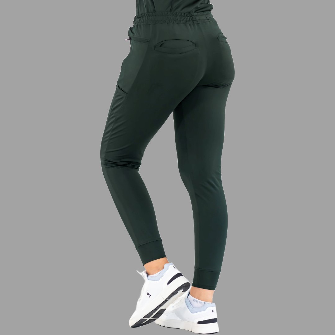 Side back view of women's scrub joggers 920 super stretch bottle green with one foot forward.