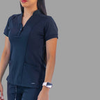 Three-quarter front view of a woman in the navy blue Style 930 scrub top, showing the side panels and front pockets.